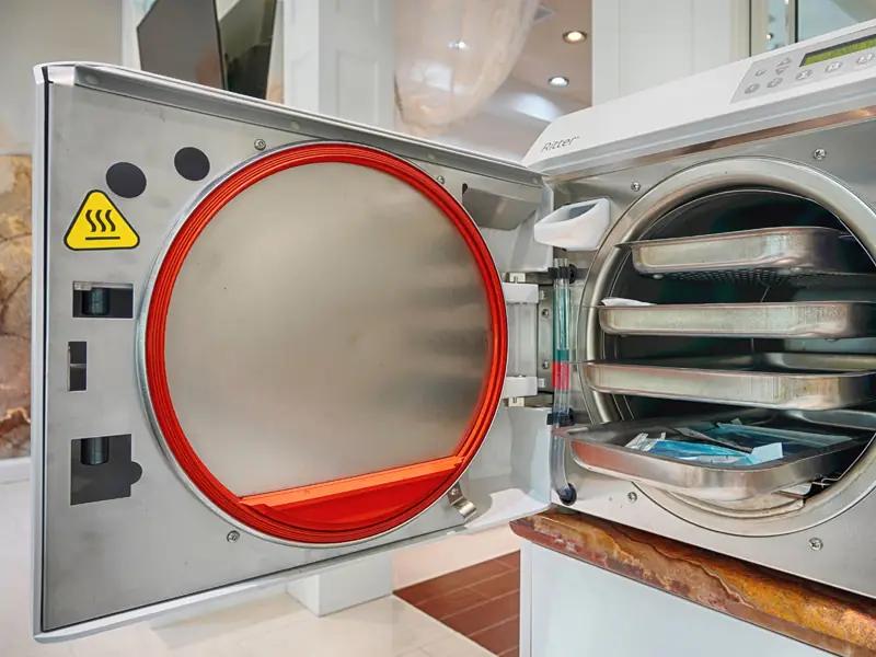 The salon's medical grade autoclave sterilizer, open with instrument trays inside
