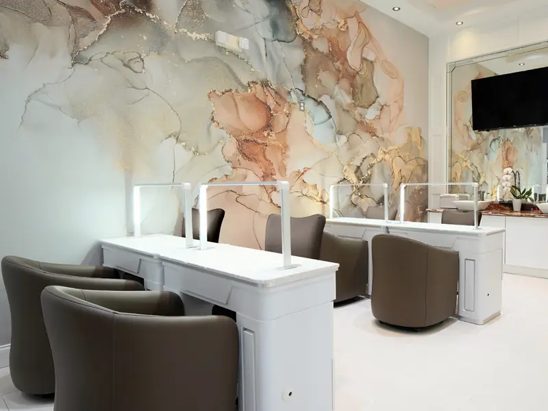 White manicure stations and espresso chairs beneath the mural wall at Tipsy Nails & Spa