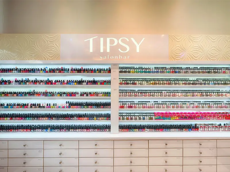 The polish wall at Tipsy Nails & Spa, hundreds of bottles under a lit Tipsy sign