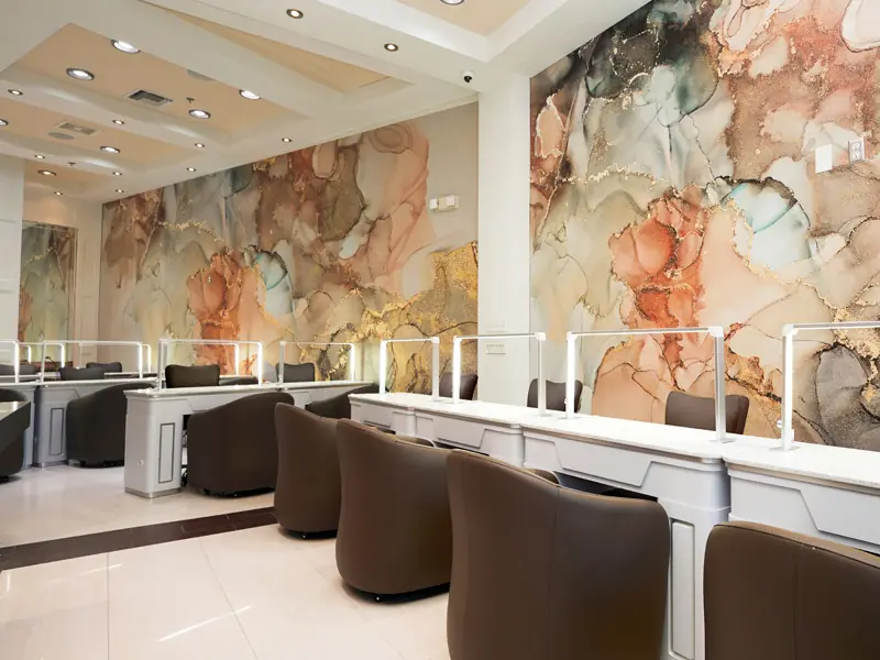 Manicure stations at Tipsy Nails & Spa in front of the salon's blush and gold mural wall